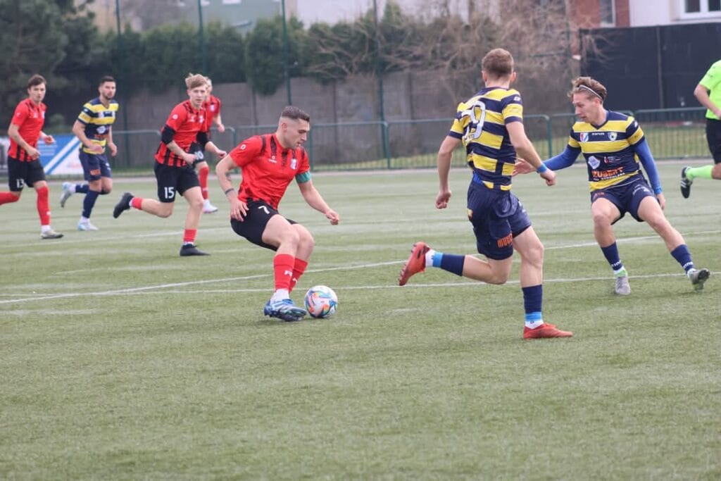 Piłkarze grają na zielonym boisku w piłkę nożną