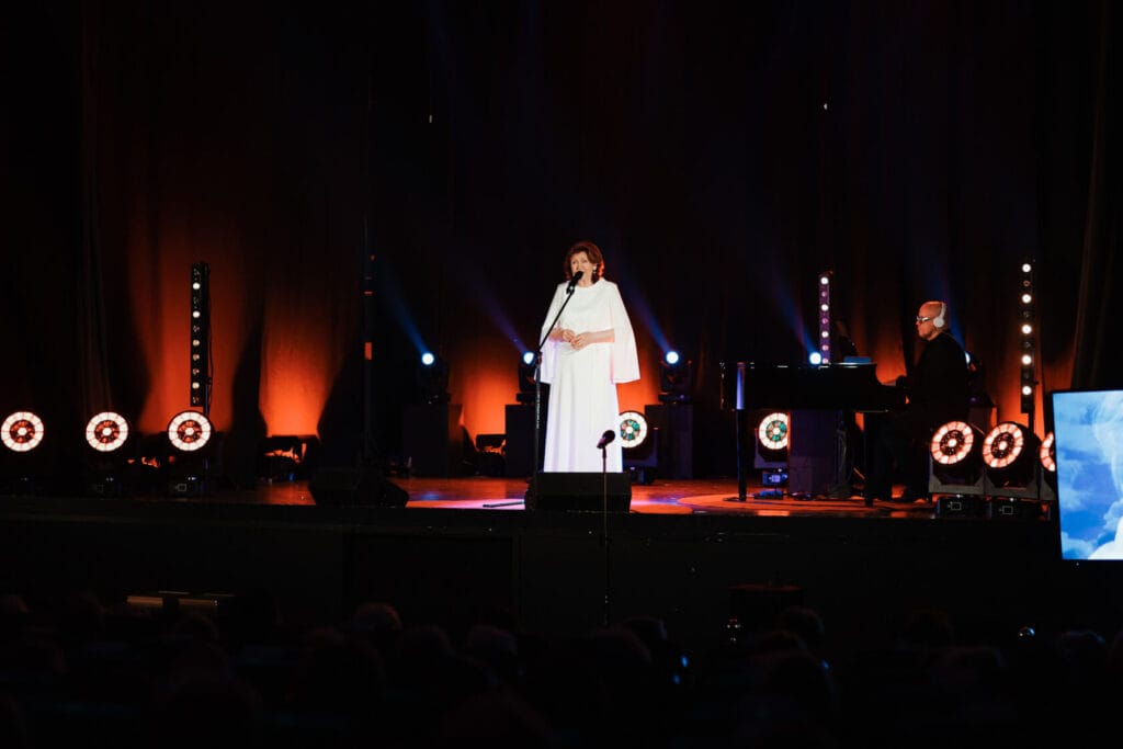 Kobieta śpiewa na scenie obok pianisty