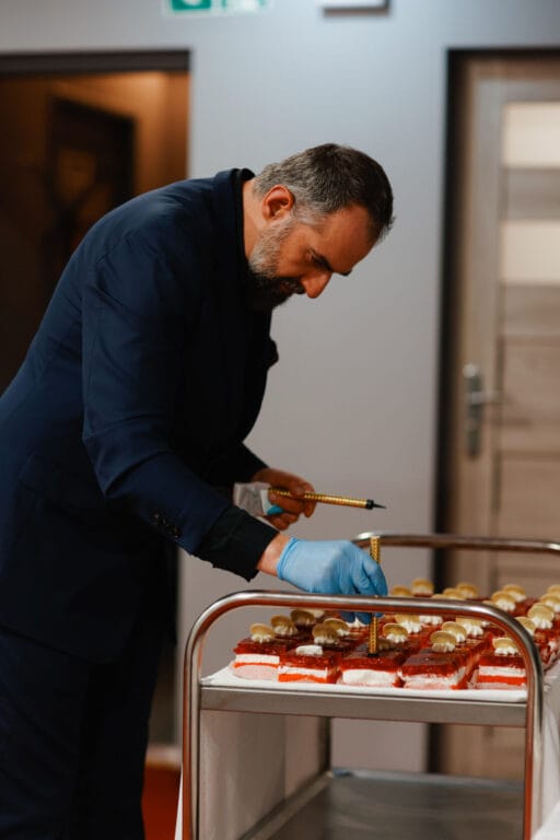 Mężczyzna w garniturze dekoruje desery na wózku