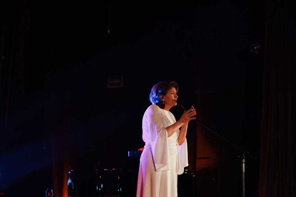 Kobieta w białej sukni śpiewa na scenie