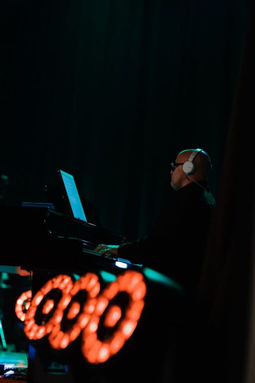 Pianista grający na koncercie przy oświetlonym pianinie