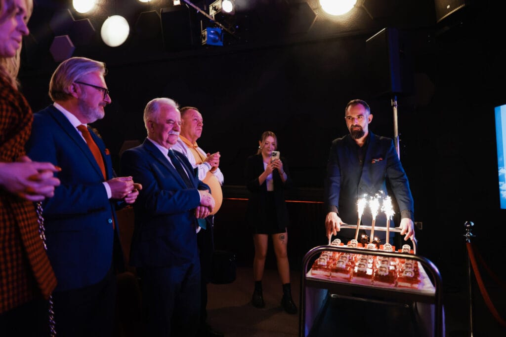 Grupa ludzi obchodzi urodziny z tortem i racami