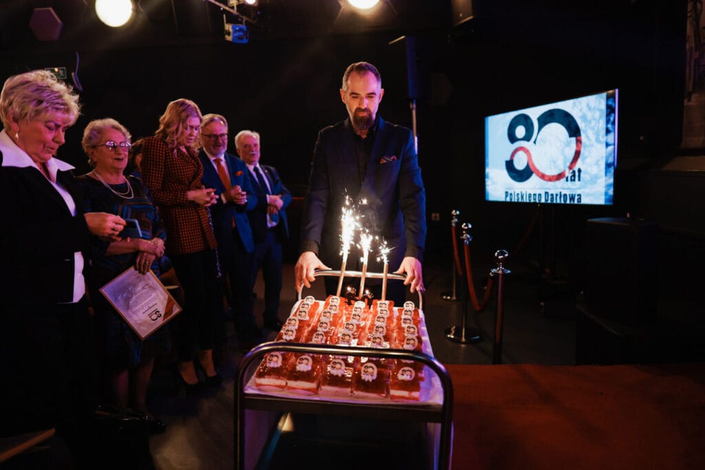 Mężczyzna przed tortem z fajerwerkami na jubileuszu