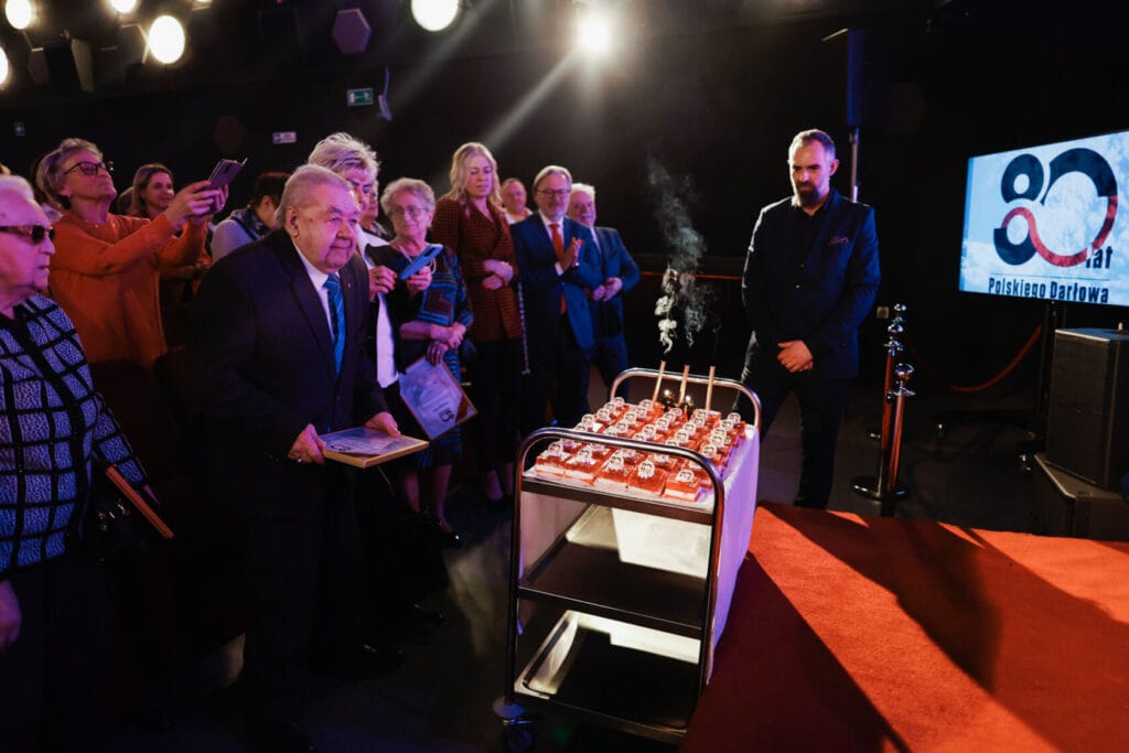 Starszy mężczyzna obserwuje tort urodzinowy w teatrze