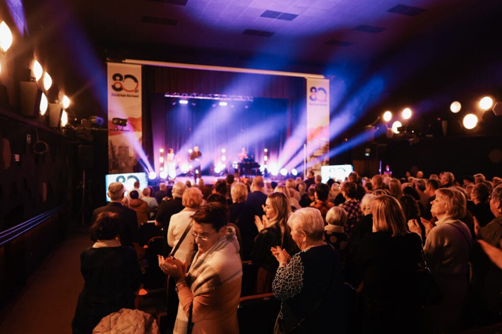 Widzowie oglądają koncert na żywo w zaciemnionym klubie