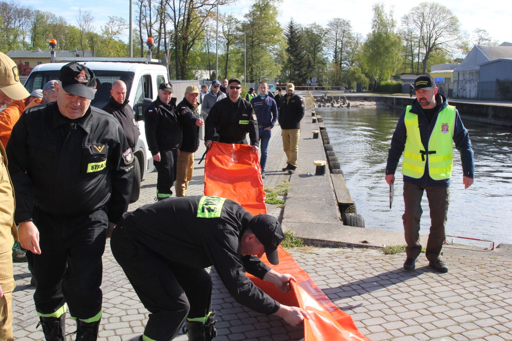IMG_0201 Strażacy przymocowują pomarańczową zapory na nabrzeżu.