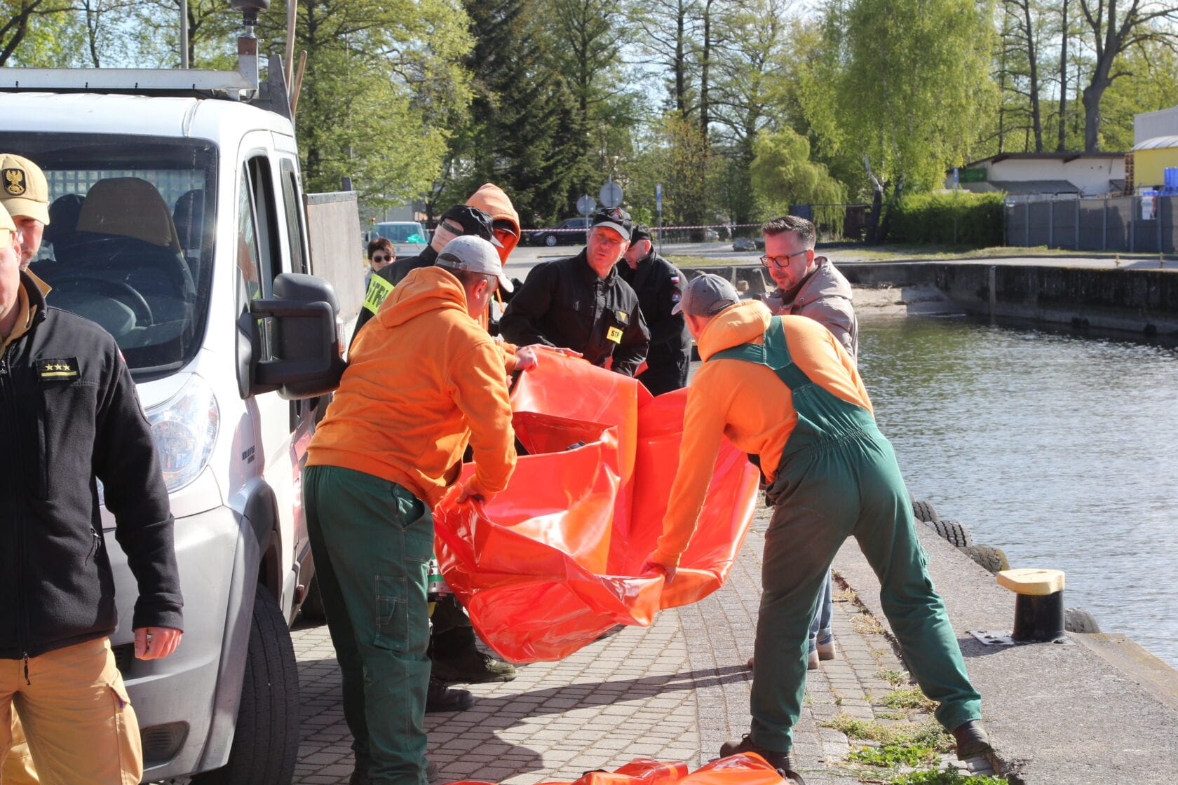 IMG_0213 Pracownicy rozwijają duży pomarańczowy worek nad wodą