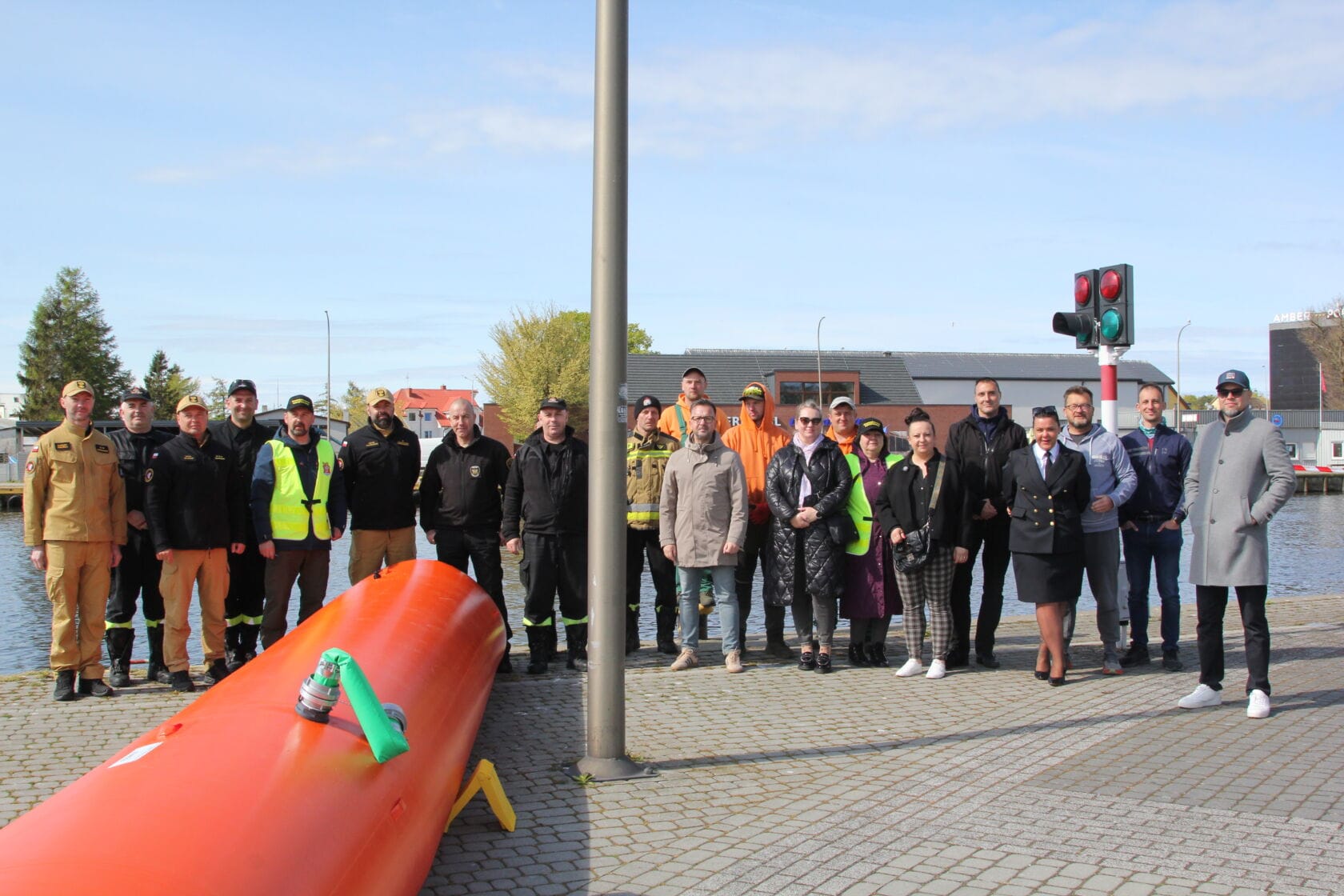 IMG_0290 Grupa ludzi przy dużym czerwonym torpedzie na nabrzeżu