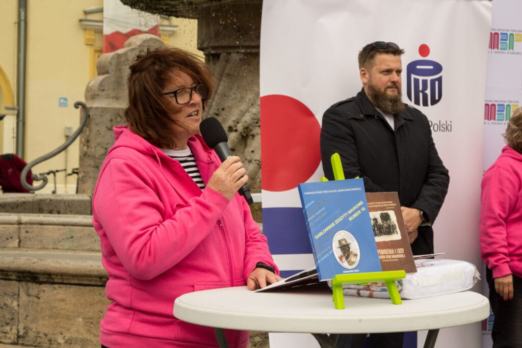 Kobieta w różowej bluzie przemawia na wydarzeniu publicznym