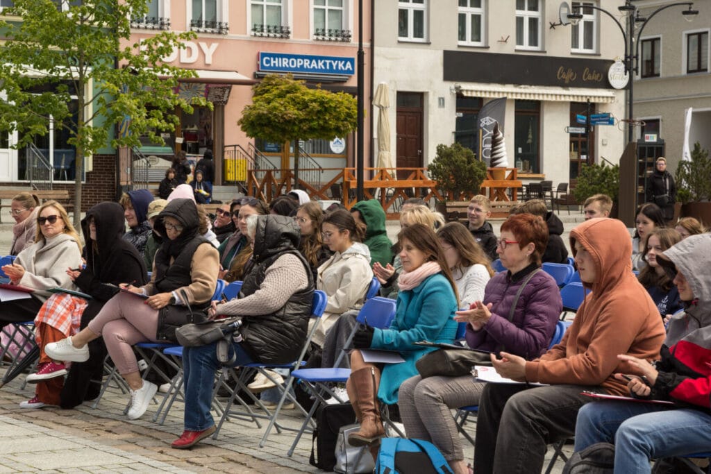 Ludzie siedzą na krzesłach na otwartym spotkaniu miejskim