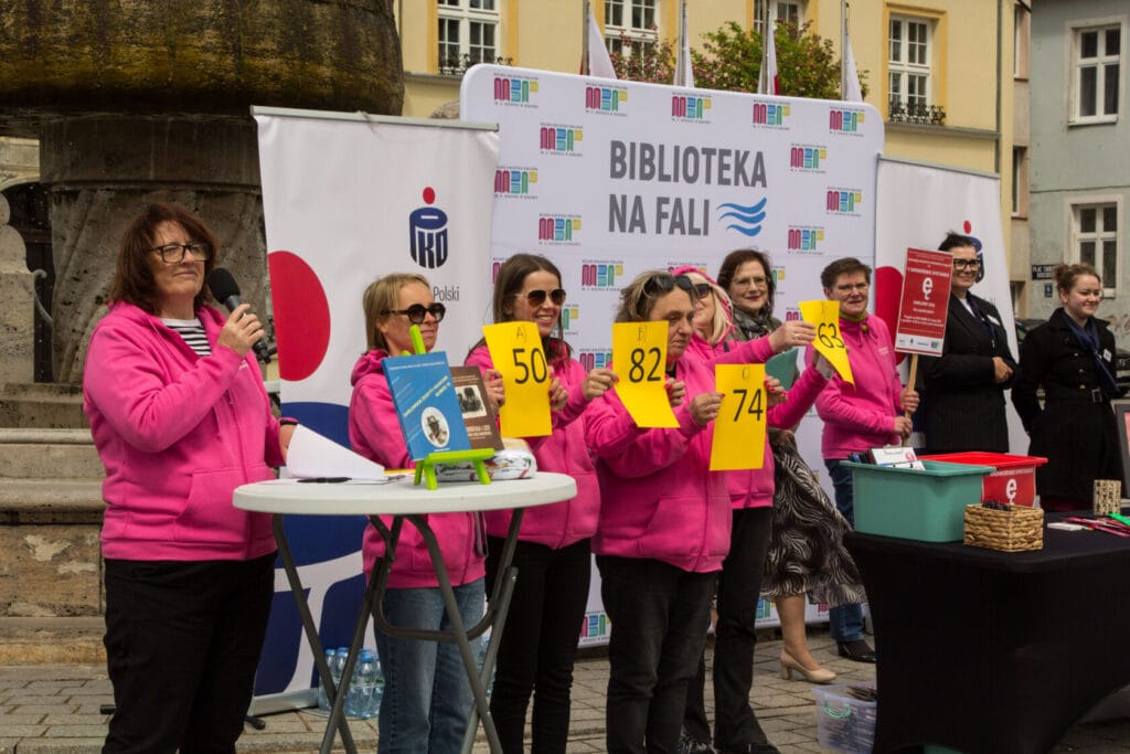 Osoby w różowych kurtkach trzymają liczby na wydarzeniu