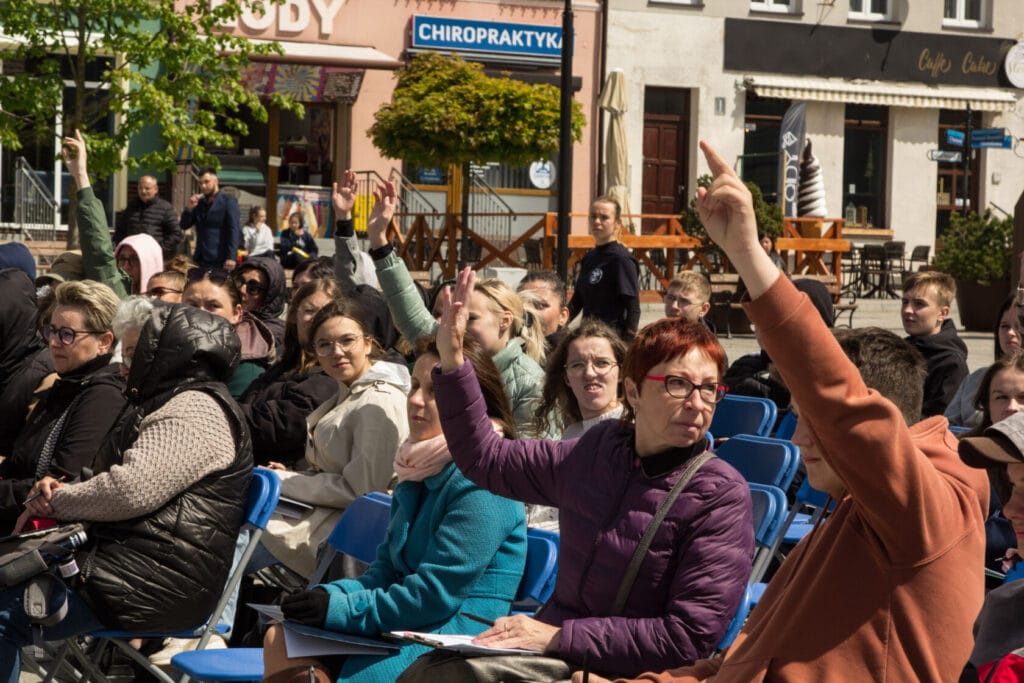 Grupa ludzi na zewnętrznym spotkaniu podnosząca ręce