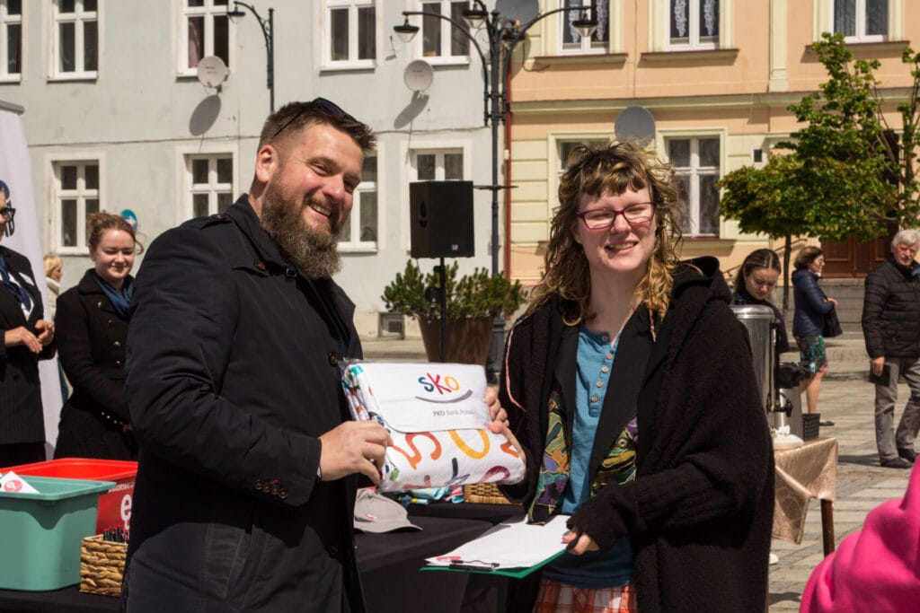 Kobieta odbiera nagrodę od mężczyzny na miejskim evencie