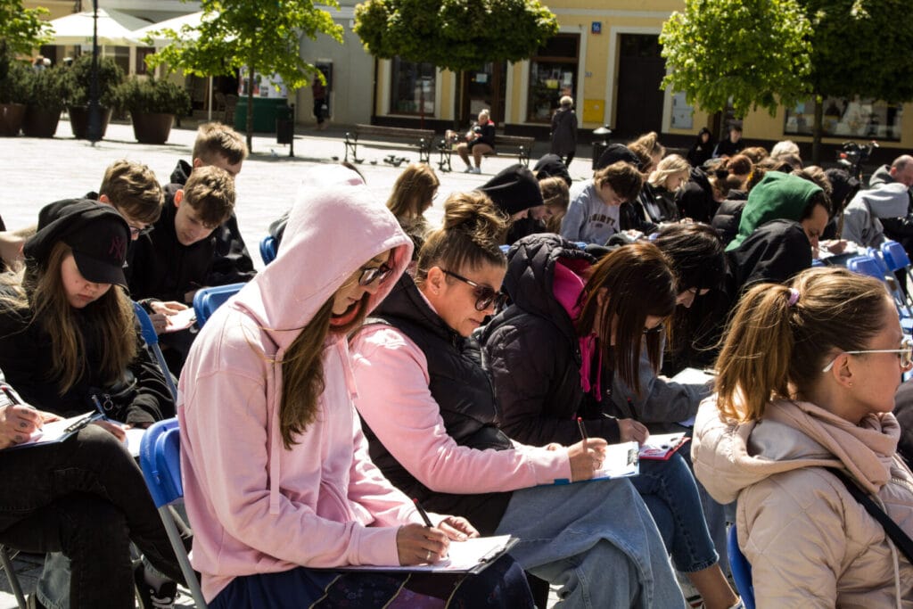 Grupa osób piszących na zewnątrz w słoneczny dzień