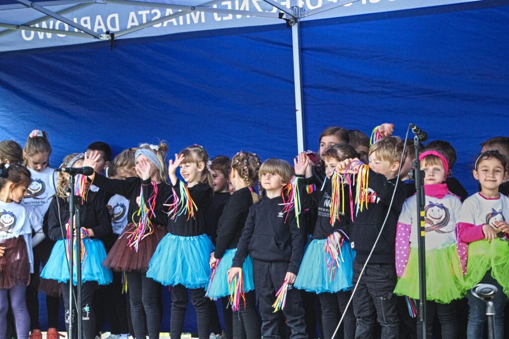 Dzieci w kolorowych spódniczkach na scenie szkolnej