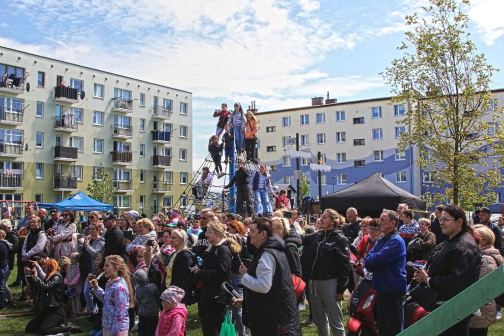 Zgromadzenie ludzi na festynie miejskim przed blokami