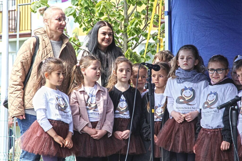 Dzieci i dorosłe osoby obserwują wydarzenie na scenie