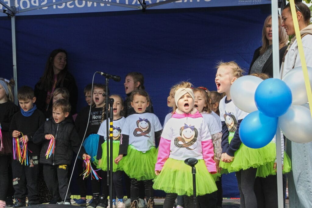 Dzieci śpiewające na scenie podczas wydarzenia na świeżym powietrzu
