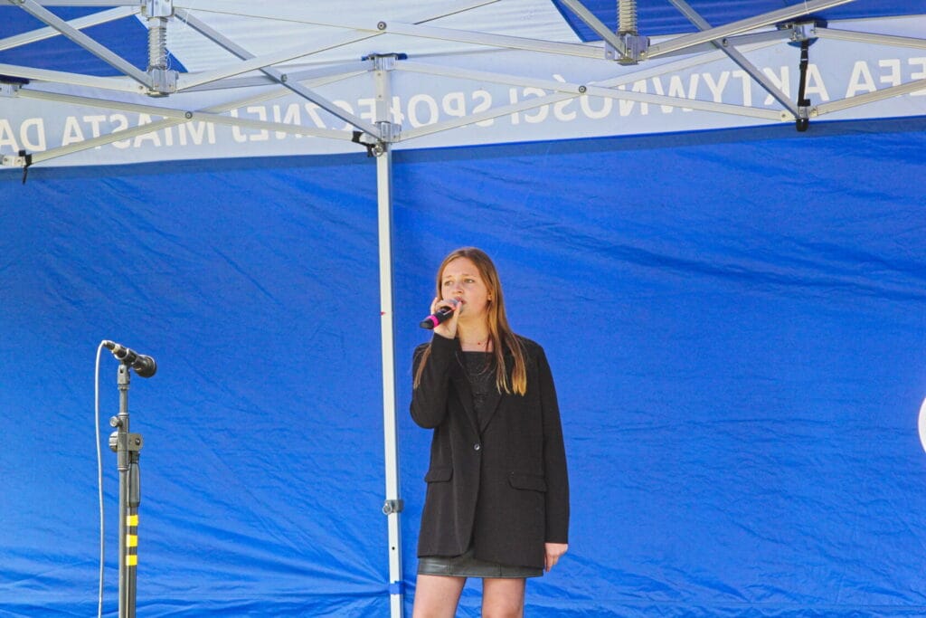 Młoda dziewczyna śpiewająca na scenie z mikrofonem