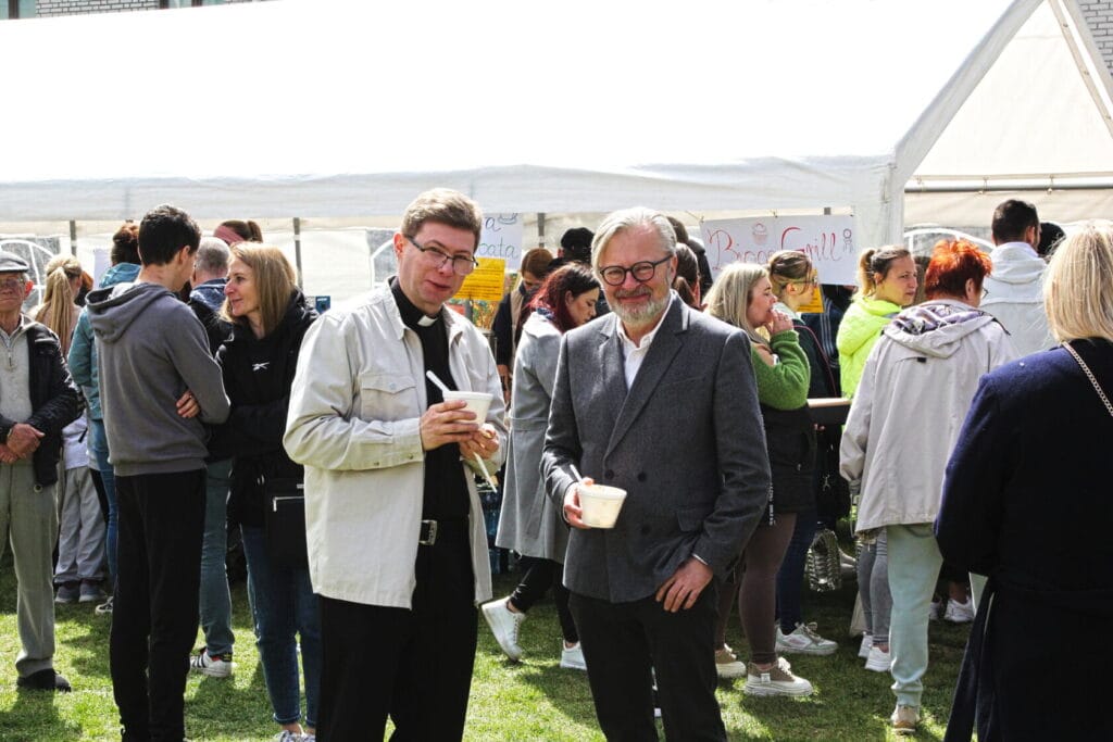 Dwóch mężczyzn rozmawia na zewnątrznym wydarzeniu społecznym