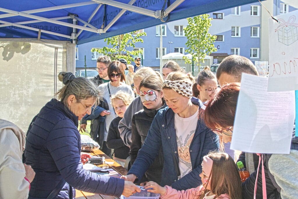 Ludzie na zewnątrz przy stoisku, dziecko z malowaniem twarzy