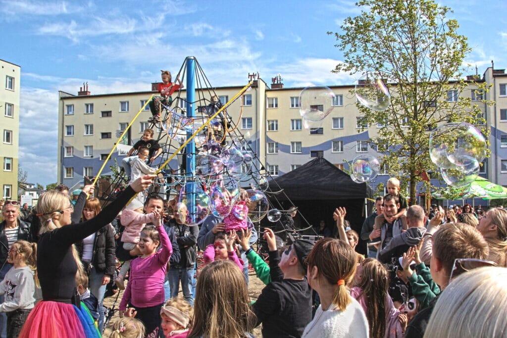 Dzieci bawią się na placu zabaw, osiedle w tle