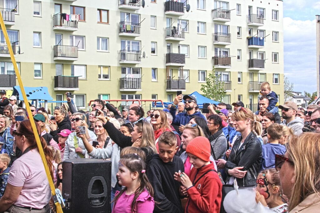 Tłum ludzi przed wielopiętrowym budynkiem na wydarzeniu