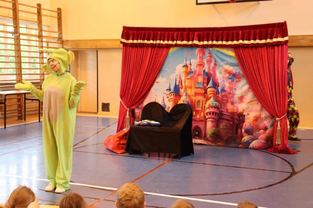 Dziecko w kostiumie smoka na szkolnej scenie