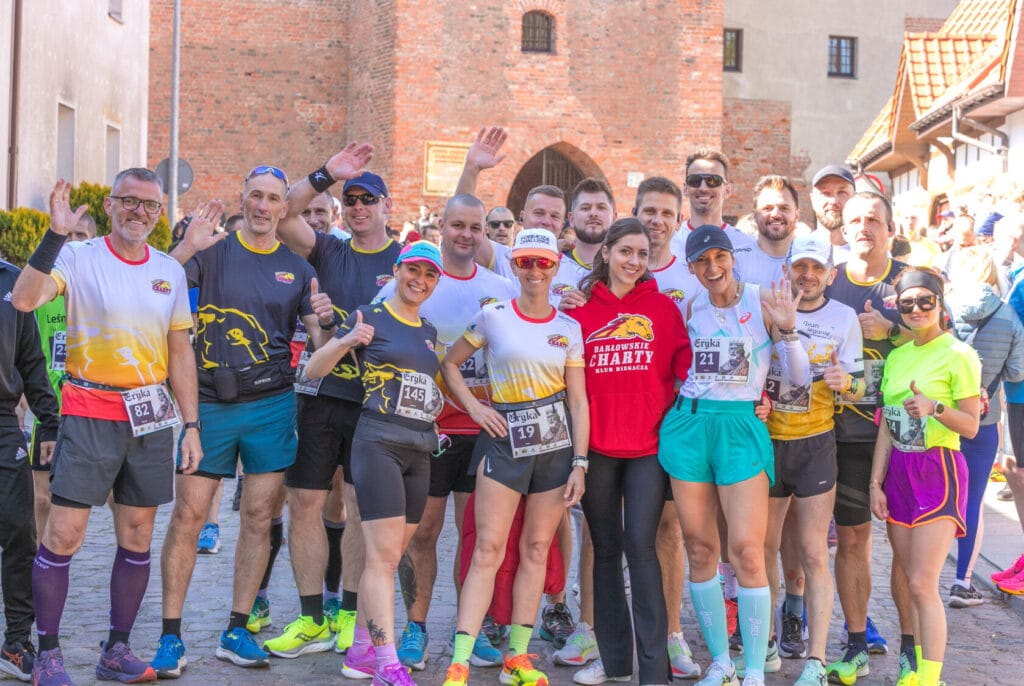 Grupa uśmiechniętych biegaczy pozująca przed biegiem
