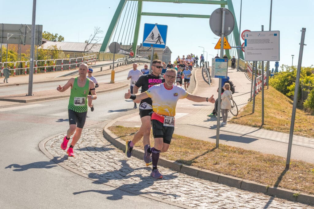 Biegacze na ulicach podczas maratonu w słoneczny dzień