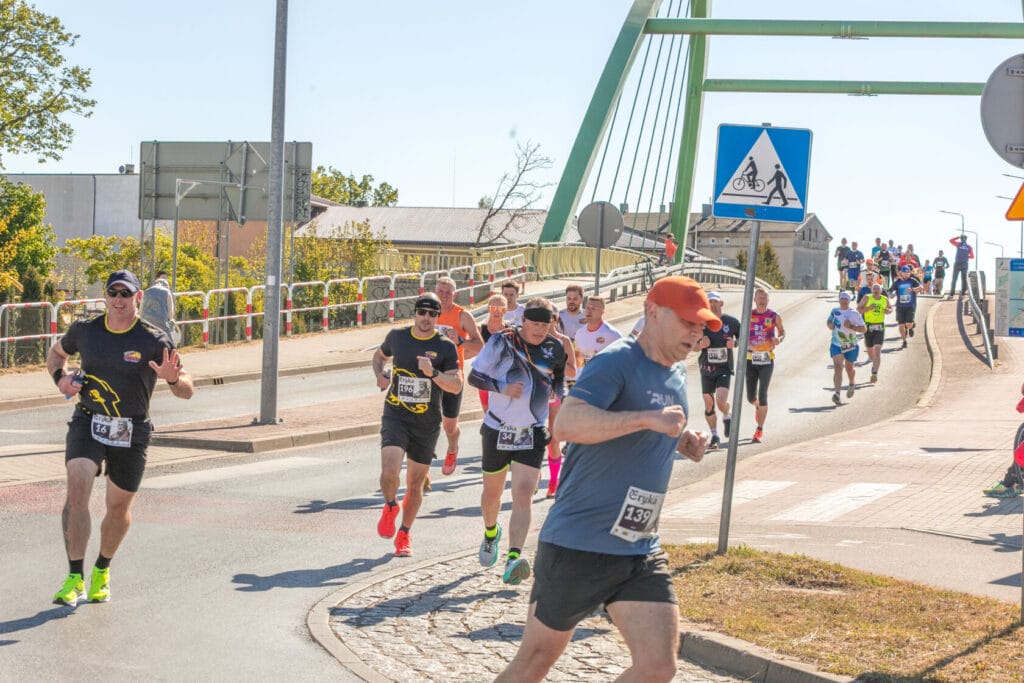 Biegacze uczestniczą w maratonie miejskim na słonecznej ulicy