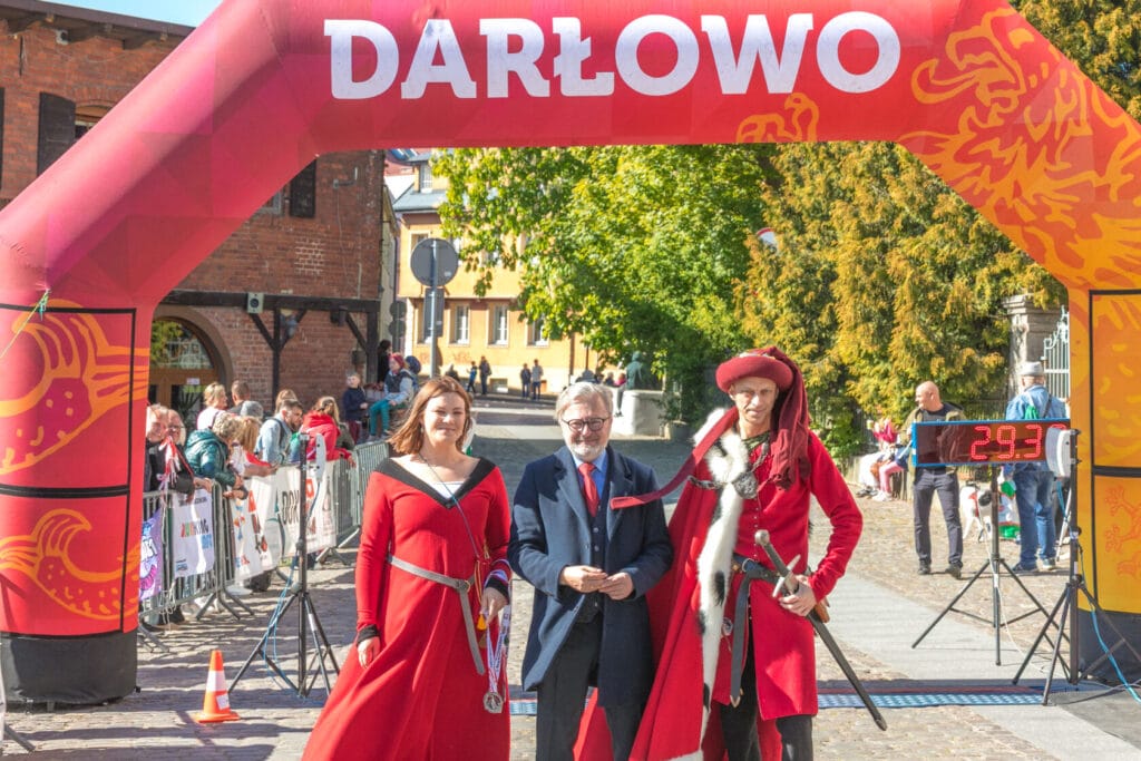 Ludzie w strojach historycznych w Darłowie pod bramą