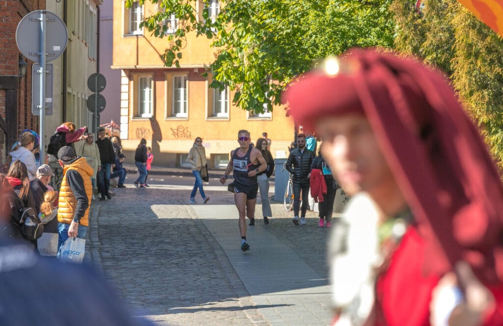 Maratończyk biegnie ulicą miasta, widzowie obserwują