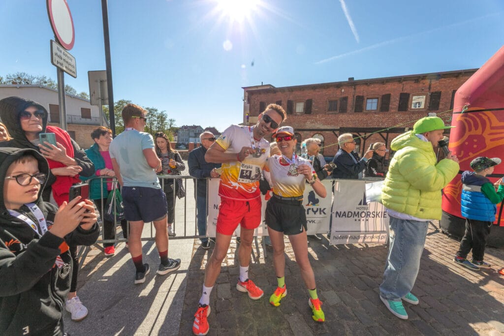 Biegacze świętują zakończenie maratonu przed zabytkowym budynkiem