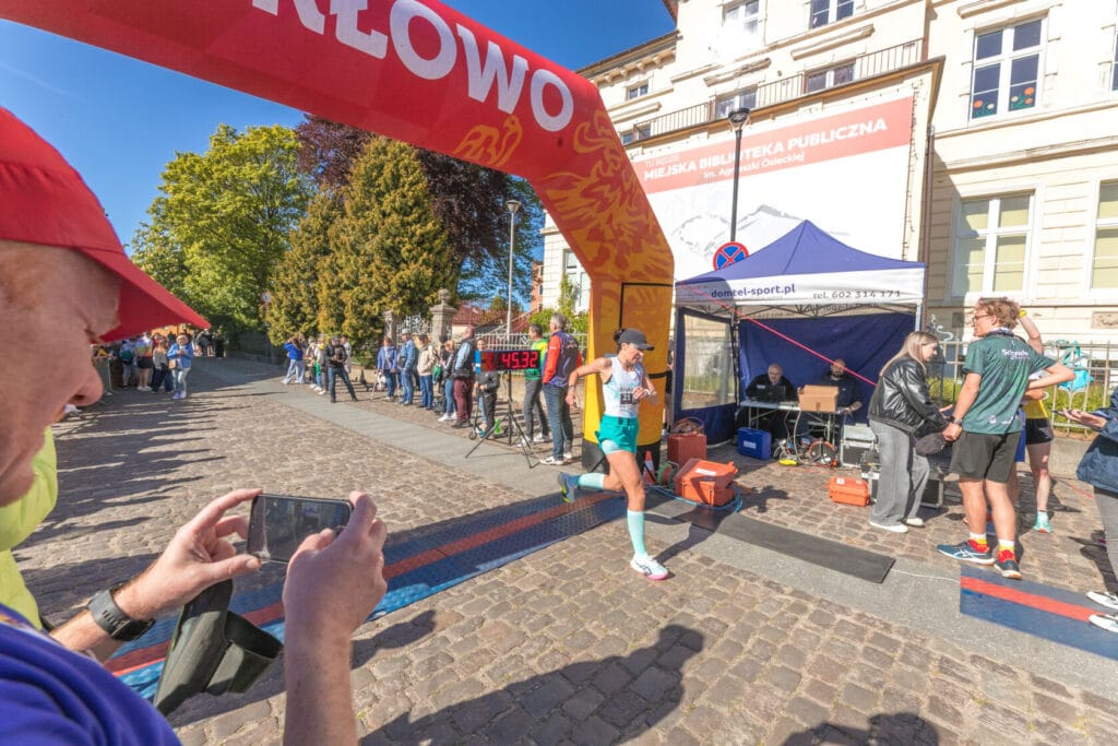 Biegacz przekracza metę maratonu, tłum obserwuje
