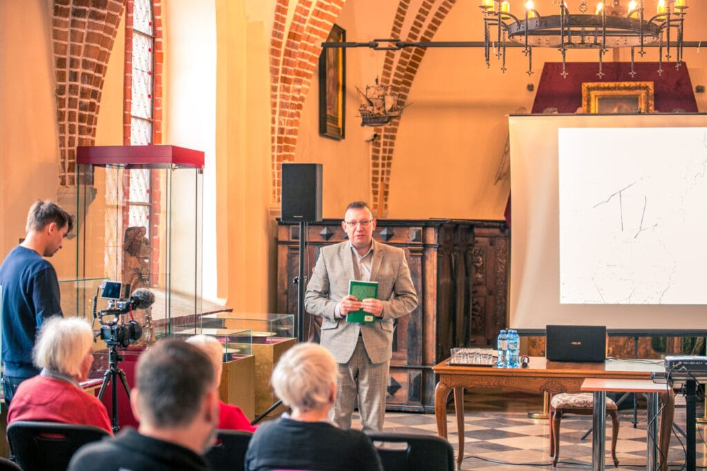 Mężczyzna prezentuje wykład w historycznym wnętrzu