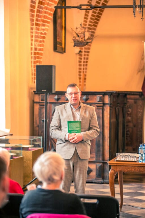 Mężczyzna prezentuje książkę na spotkaniu