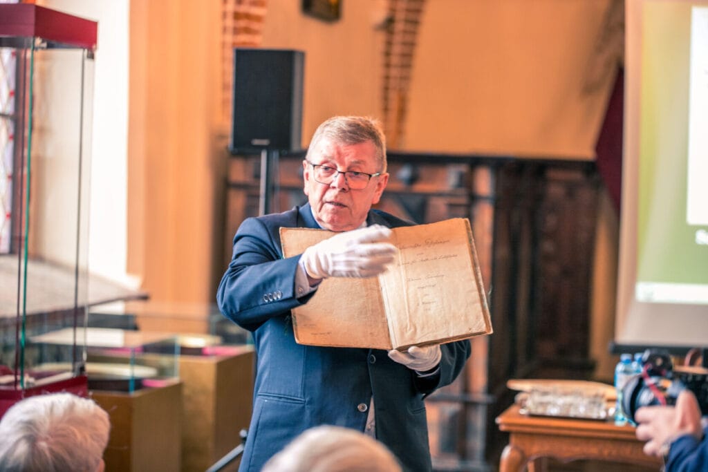 Mężczyzna prezentuje starą księgę na wykładzie