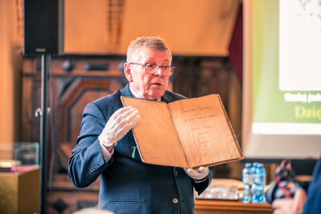 Mężczyzna prezentuje starą księgę na konferencji