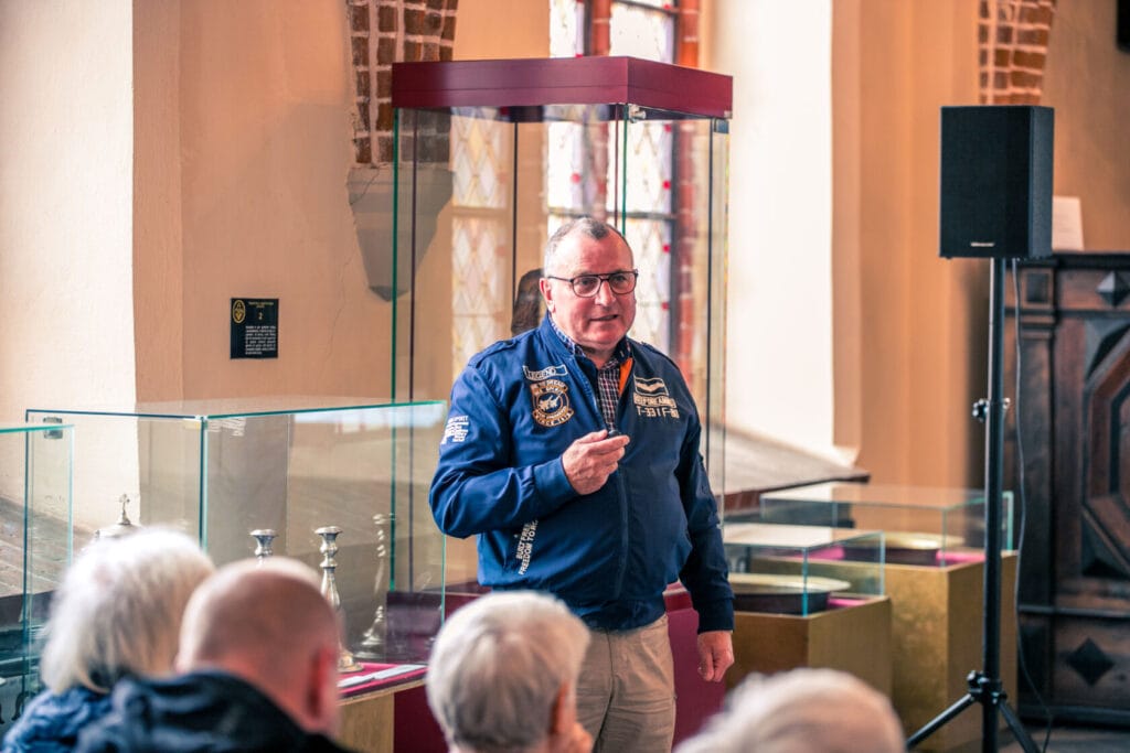 Mężczyzna w niebieskiej kurtce wygłasza prezentację