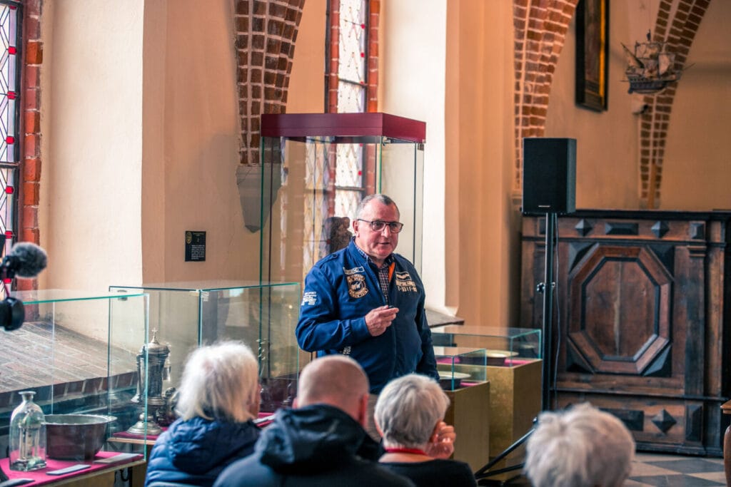 Mężczyzna w mundurze przemawia do grupy osób