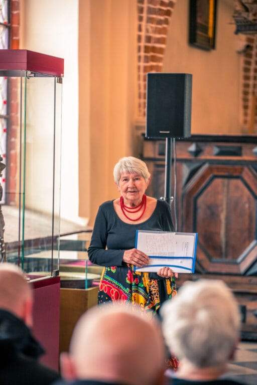 Starsza kobieta przemawia na wydarzeniu w kościele