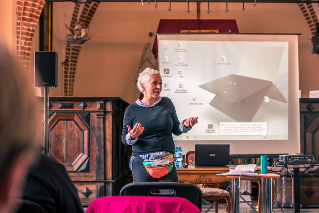 Starsza kobieta prezentuje laptopa na konferencji