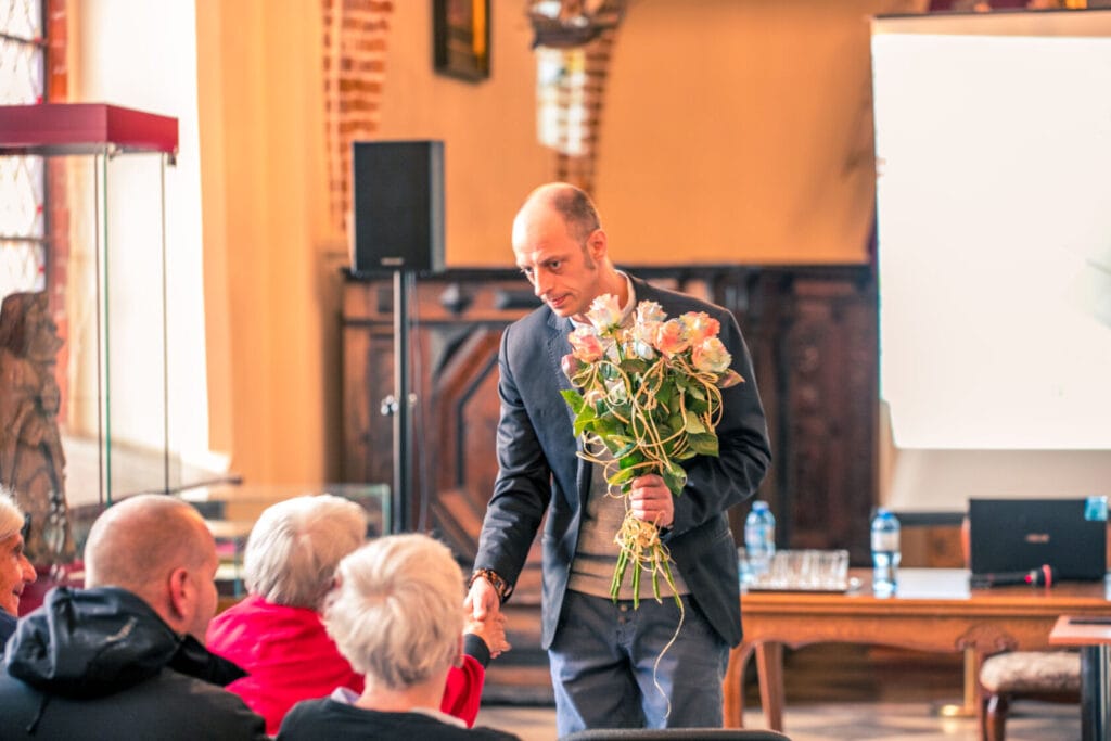 Mężczyzna wręcza kwiaty słuchaczom na seminarium