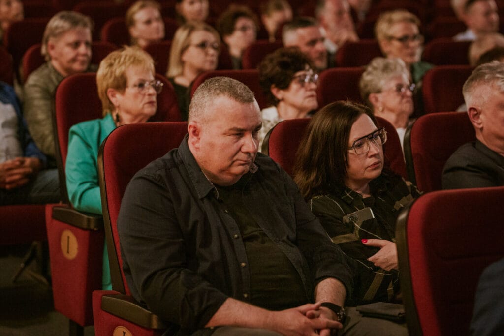 Dorośli słuchający prezentacji w teatrze.