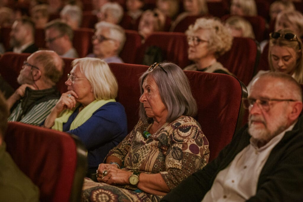 Starsi ludzie oglądający film w kinie.