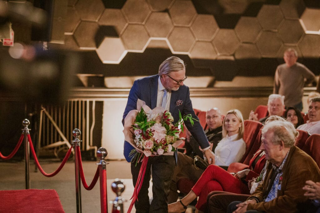 Mężczyzna wręcza kwiaty podczas wydarzenia w teatrze