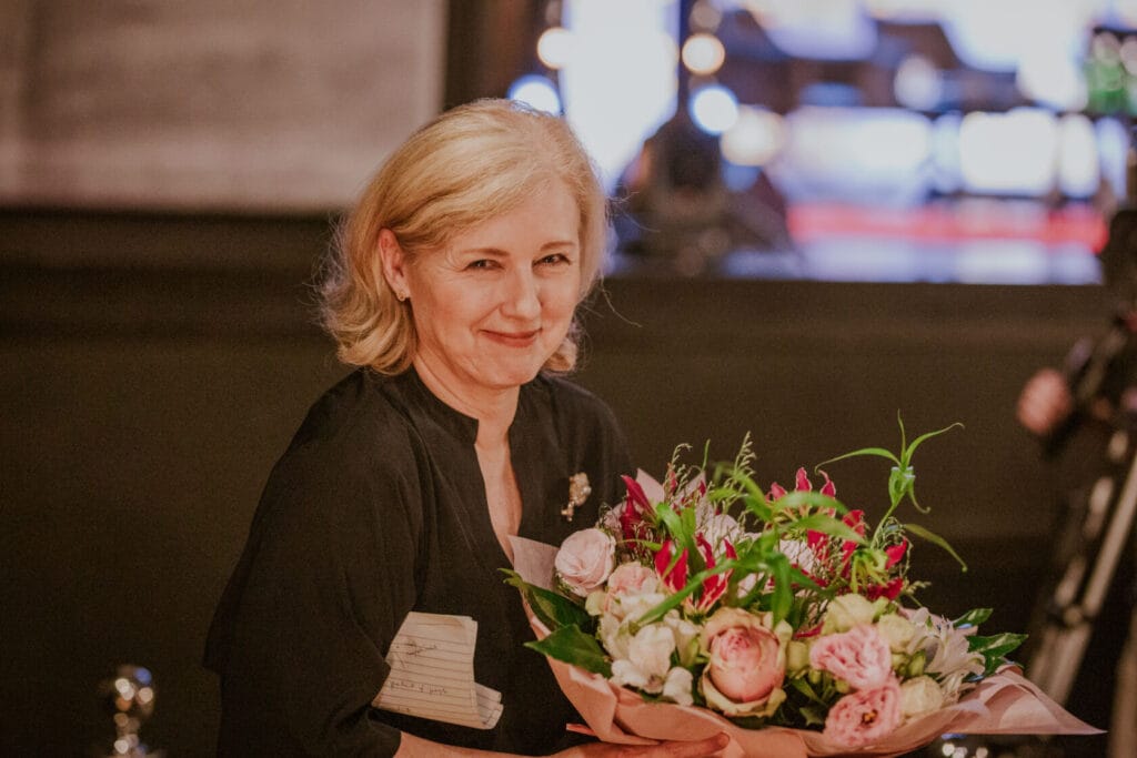 Kobieta z bukietem kwiatów uśmiecha się przyjemnie