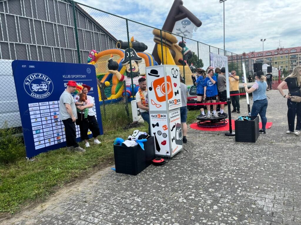 Ludzie bawią się na festynie, dmuchane zabawki w tle