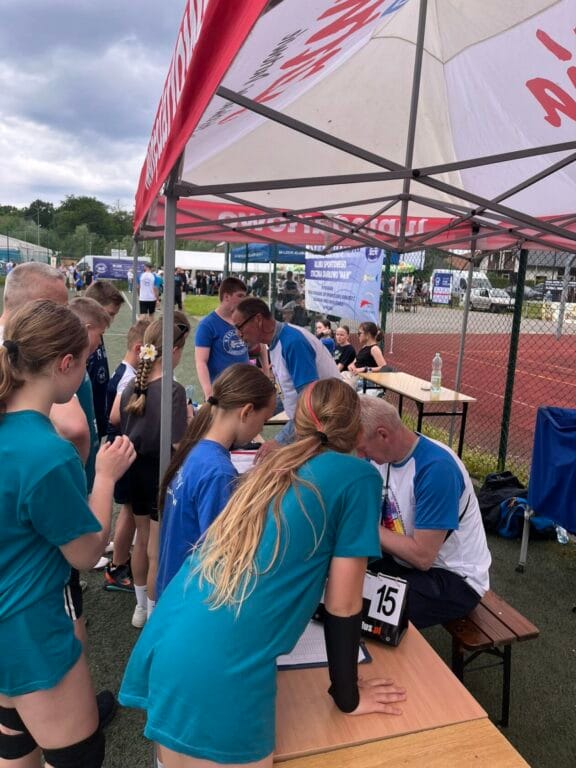 Zawodnicy pod parasolem rejestrują się na wydarzenie sportowe